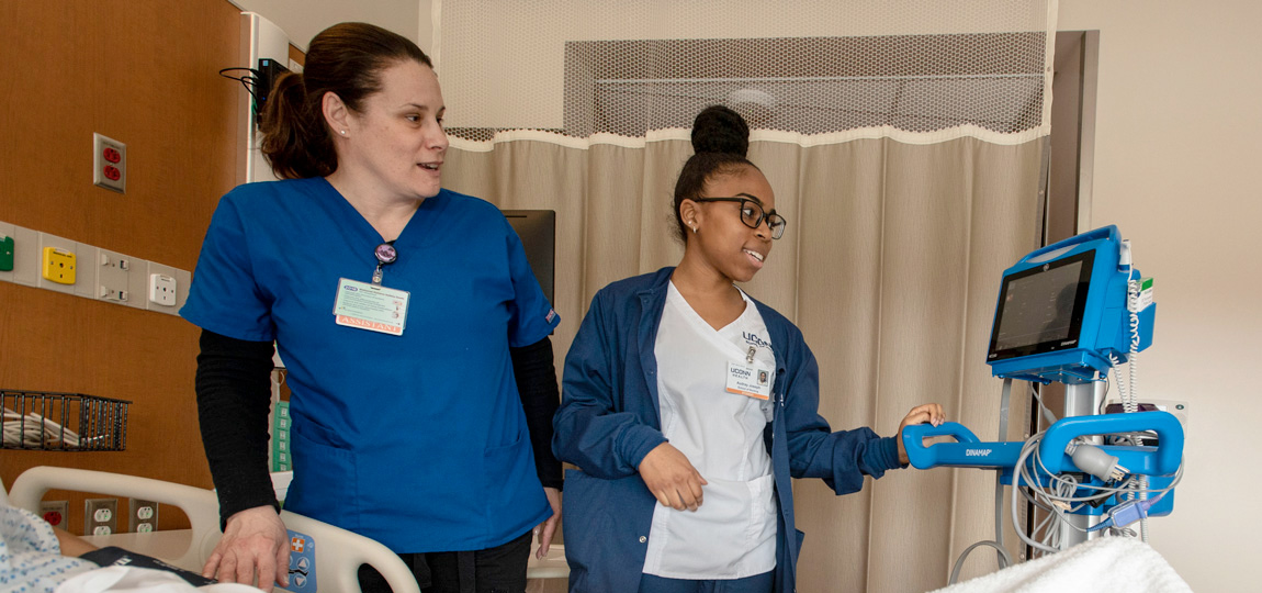 nursing students looking at a machine in the hospital